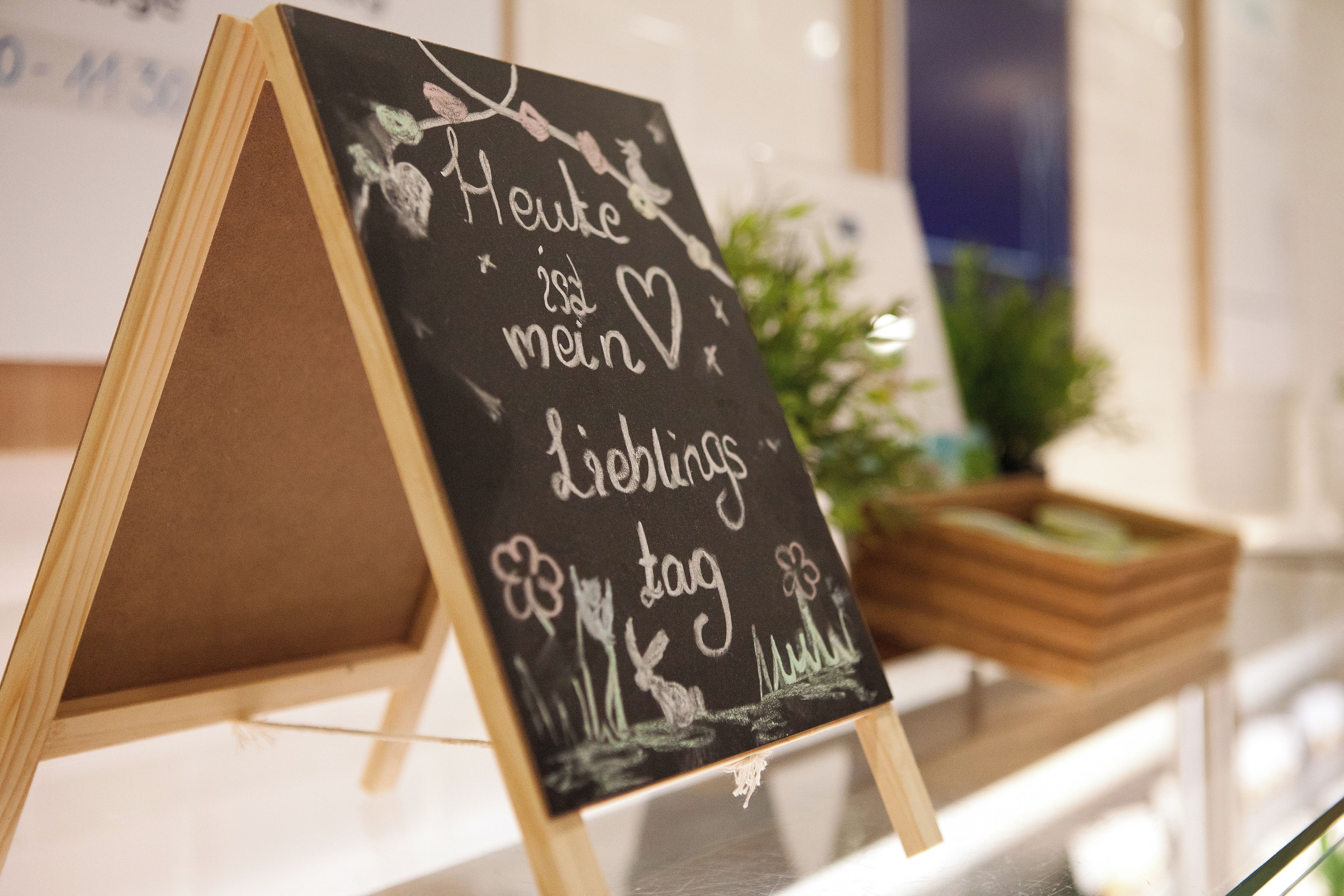 A chalkboard with handwritten text, possibly a sign or message, placed on a stand.