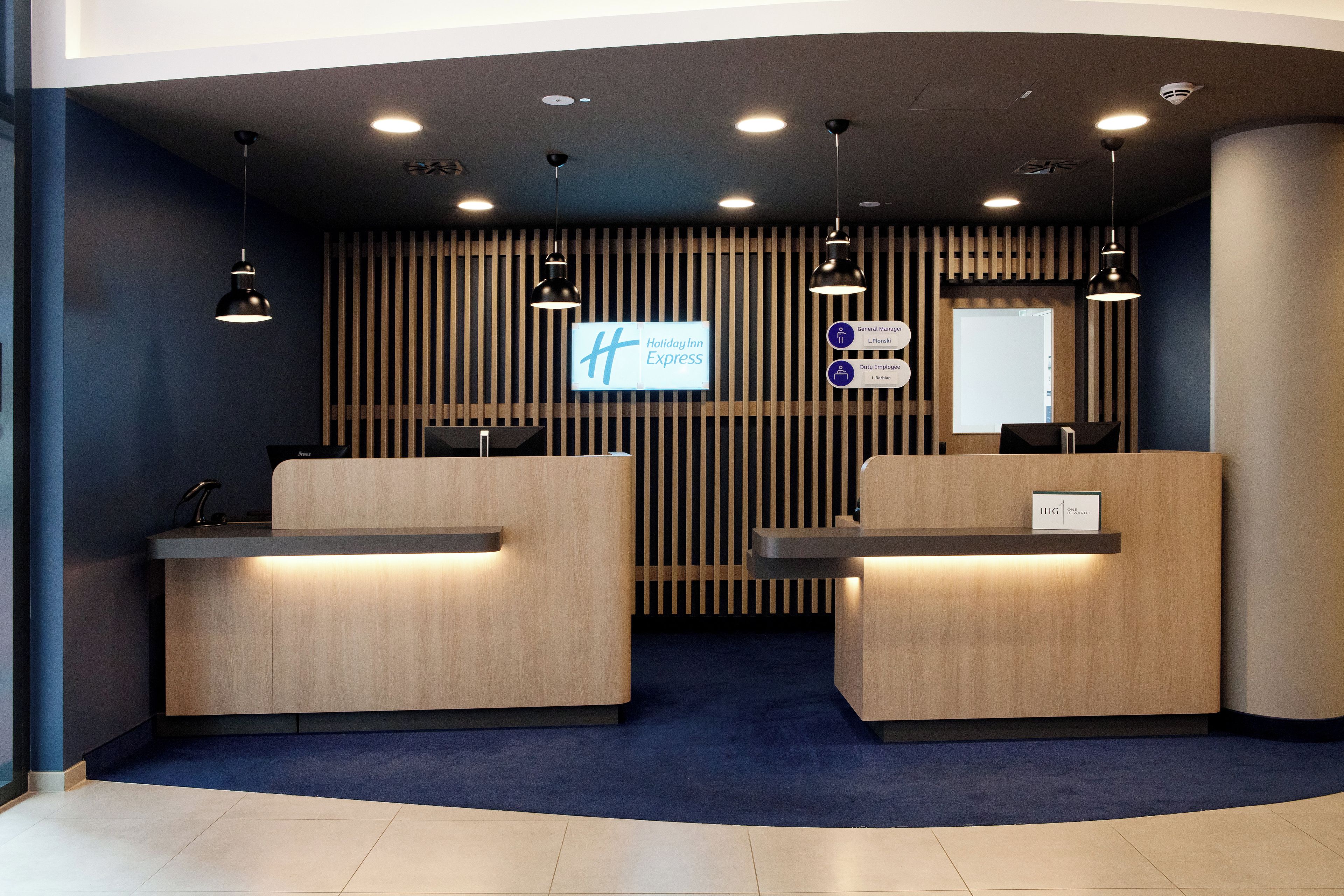 A reception desk area with two counters, a digital display, and a sign indicating 'Holiday Inn Express'.