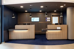 A reception desk area with two counters, a digital display, and a sign indicating 'Holiday Inn Express'. - Holiday Inn Express Recklinghausen by IHG (Recklinghausen)