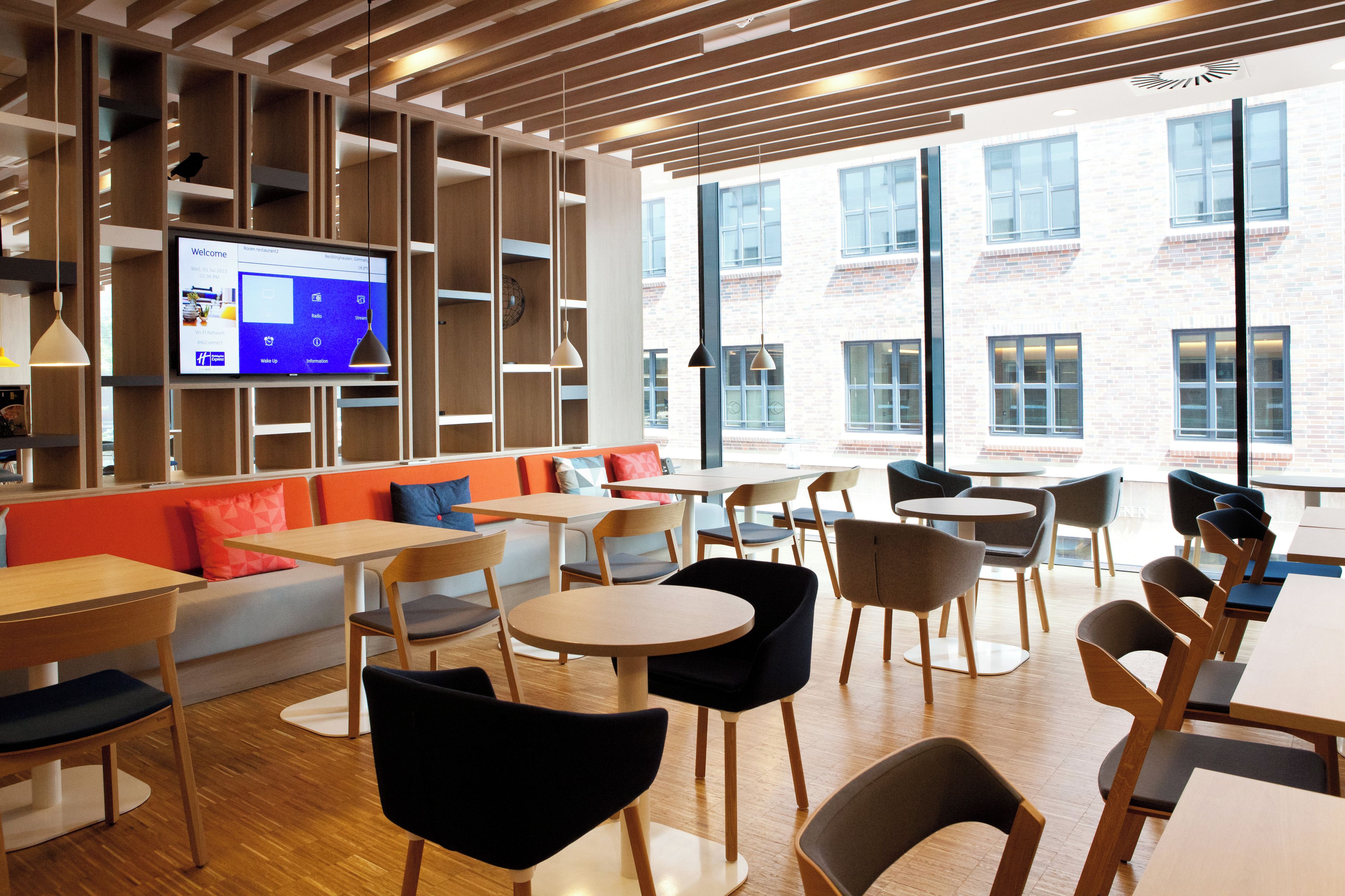 A modern interior with wooden paneling, seating areas, and a large window providing a view of a brick building.