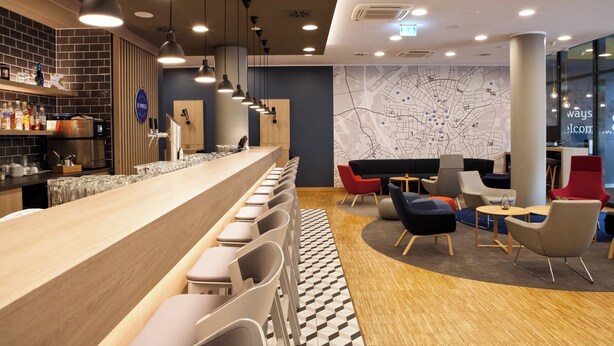 A modern bar area with a long counter, multiple seating options, and a map on the wall. - Holiday Inn Express Recklinghausen by IHG (Recklinghausen)