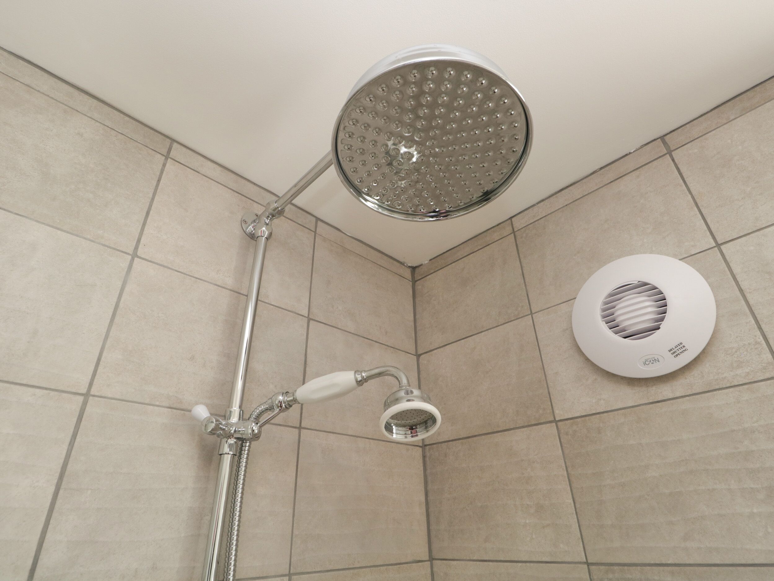 A shower with a handheld showerhead and a wall-mounted rain showerhead.
