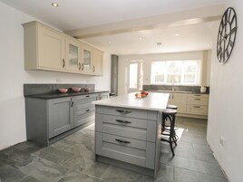A modern kitchen with grey cabinets, a central island with drawers, and a large clock on the wall.