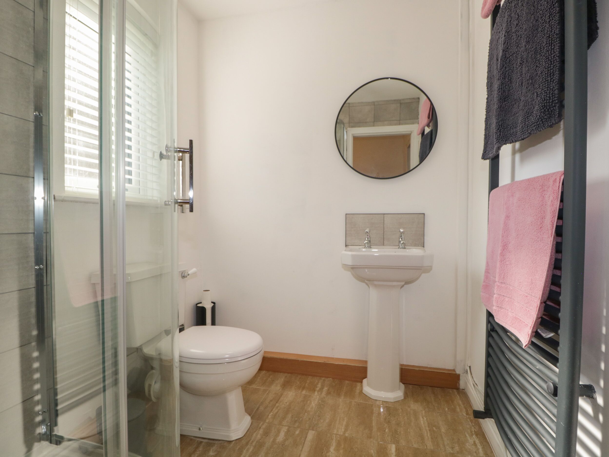 A bathroom with a toilet, sink, and a glass shower enclosure.