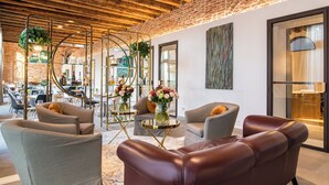 A modern interior with leather sofas, a brick wall, and a glass door. - Hotel Ristorante Magia del Brenta (Fiesso d'Artico)