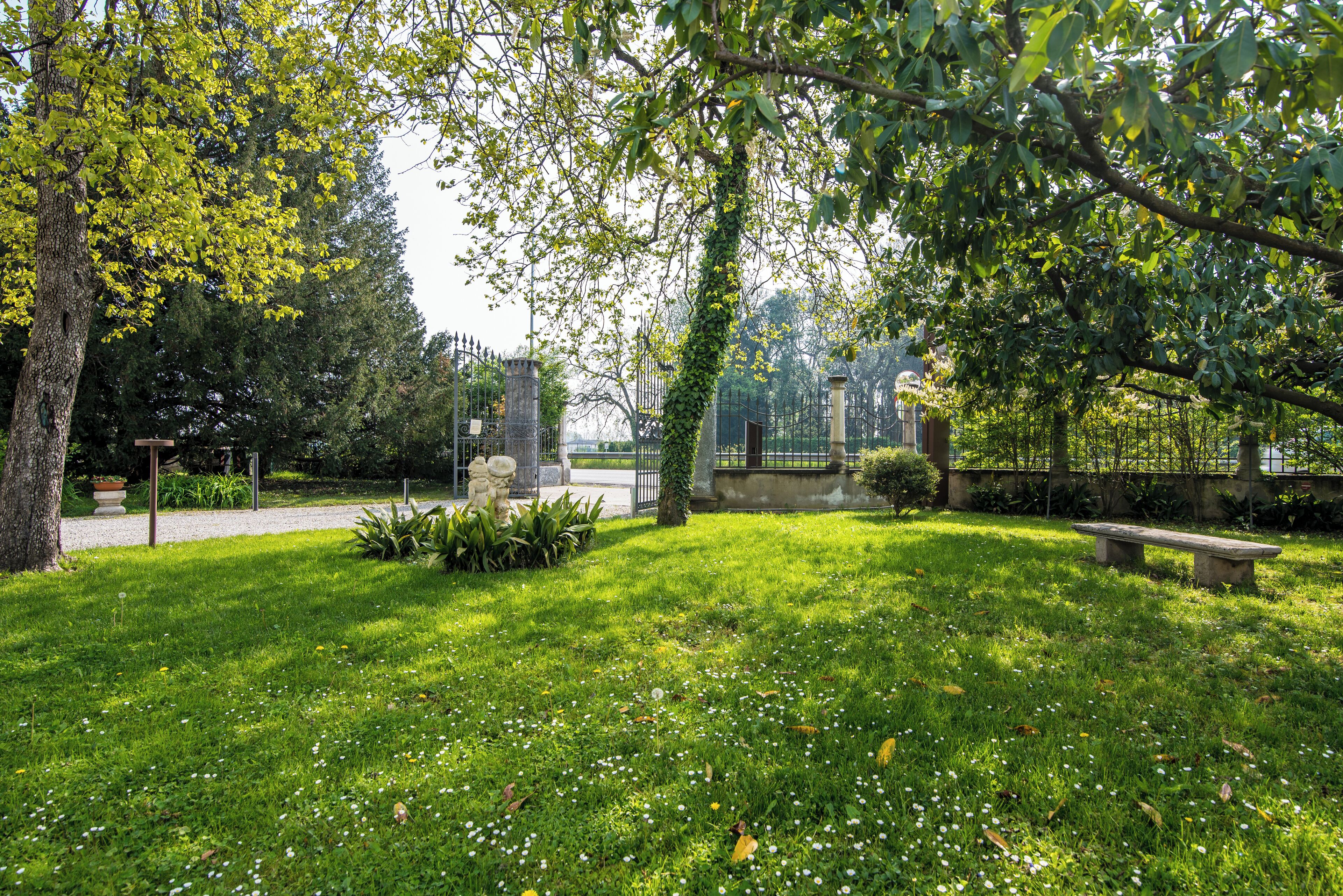 A park with a grassy area, a stone statue, and a bench.