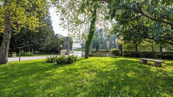 A park with a grassy area, a stone statue, and a bench.