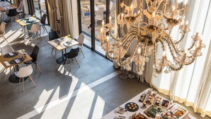 A dining area with a buffet table, elegant chandelier, and large windows offering a view of the outdoors. - Hotel Ristorante Magia del Brenta (Fiesso d'Artico)