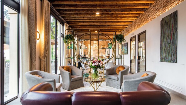 A modern interior with a wooden ceiling, large windows, and a central seating area with a table and flowers. - Hotel Ristorante Magia del Brenta (Fiesso d'Artico)