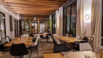 Un ristorante con tavoli e sedie in legno, ampie finestre e un design moderno.
