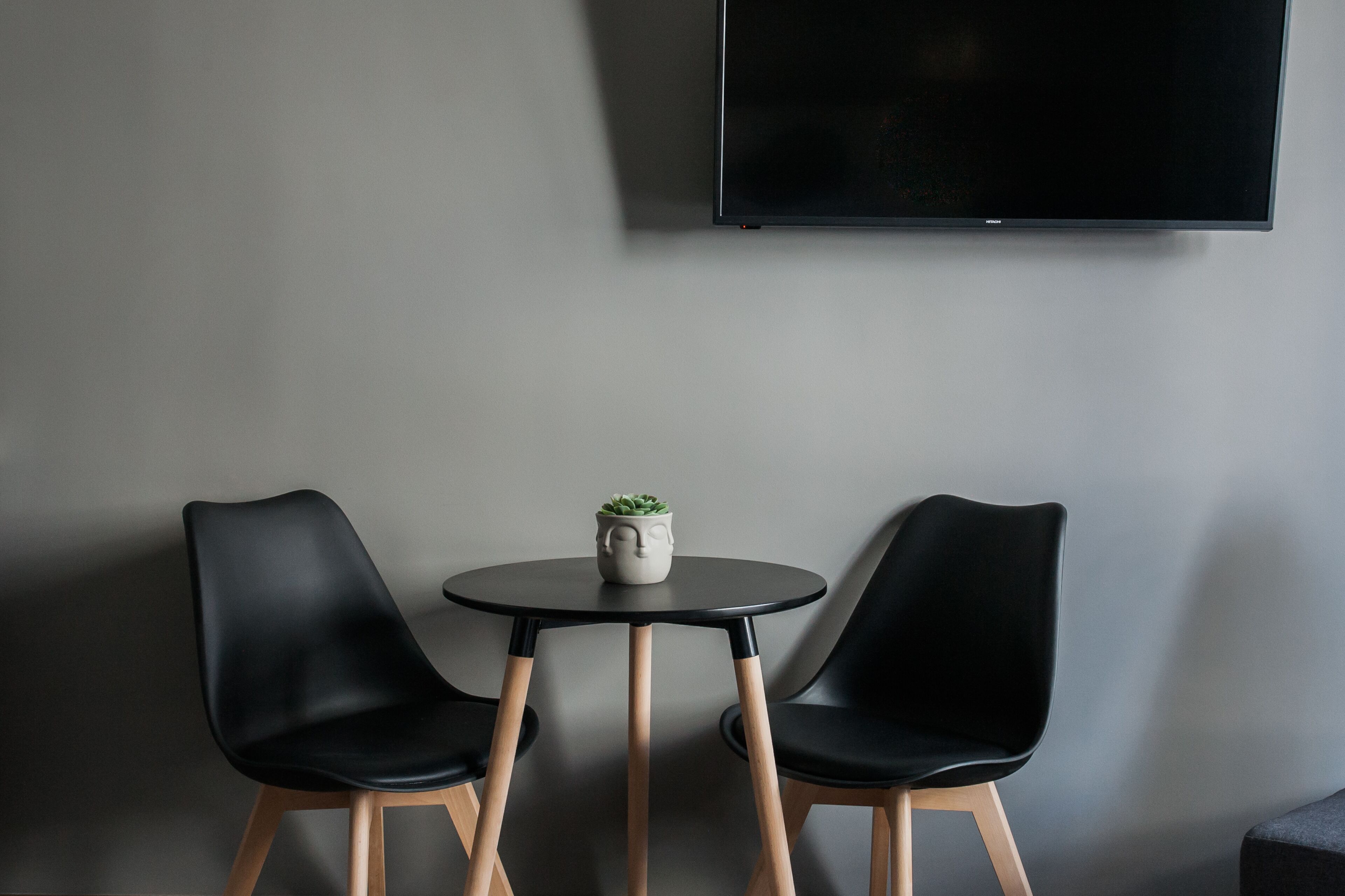 A modern room with two black chairs, a small round table, and a potted plant.