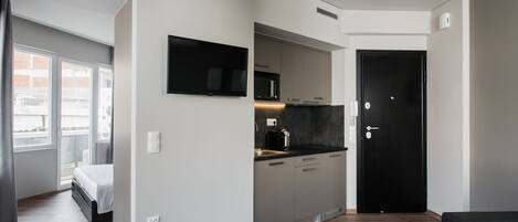 A modern apartment with a kitchenette, a bed, a black sofa, and a dining area.