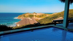 A pool with a view of the ocean and hills. - The Beach House at Praia da Rocha (Inhambane)