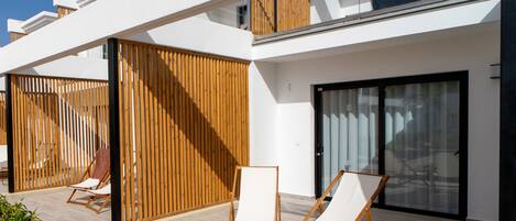 Un espacio al aire libre moderno con dos sillones reclinables y una valla de madera.