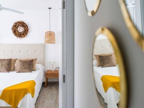 Un dormitorio moderno con cabecera acolchada, una mesita de noche con un florero y una lámpara colgante.