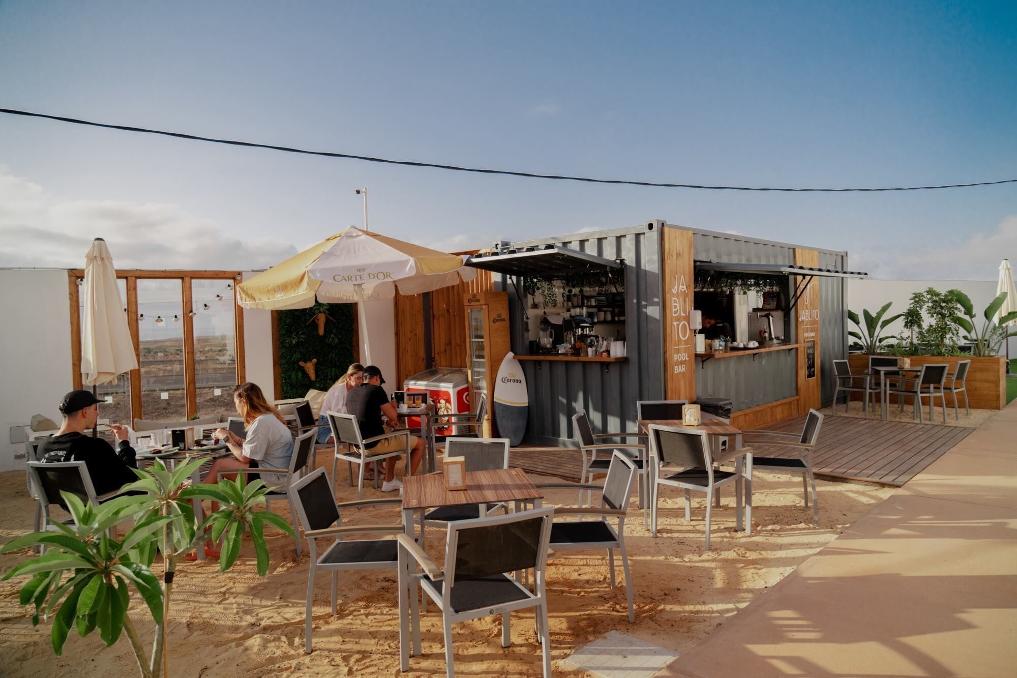 An outdoor seating area with tables and chairs, a bar area, and a view of the landscape.