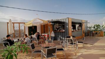 Un área de estar al aire libre con mesas y sillas, un bar y vistas del paisaje.