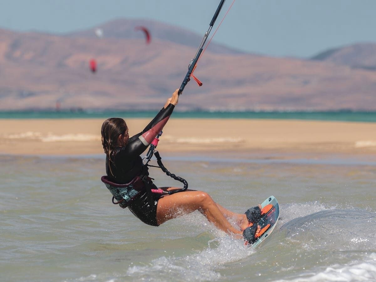 A person windsurfing on a clear day with mountains in the background.