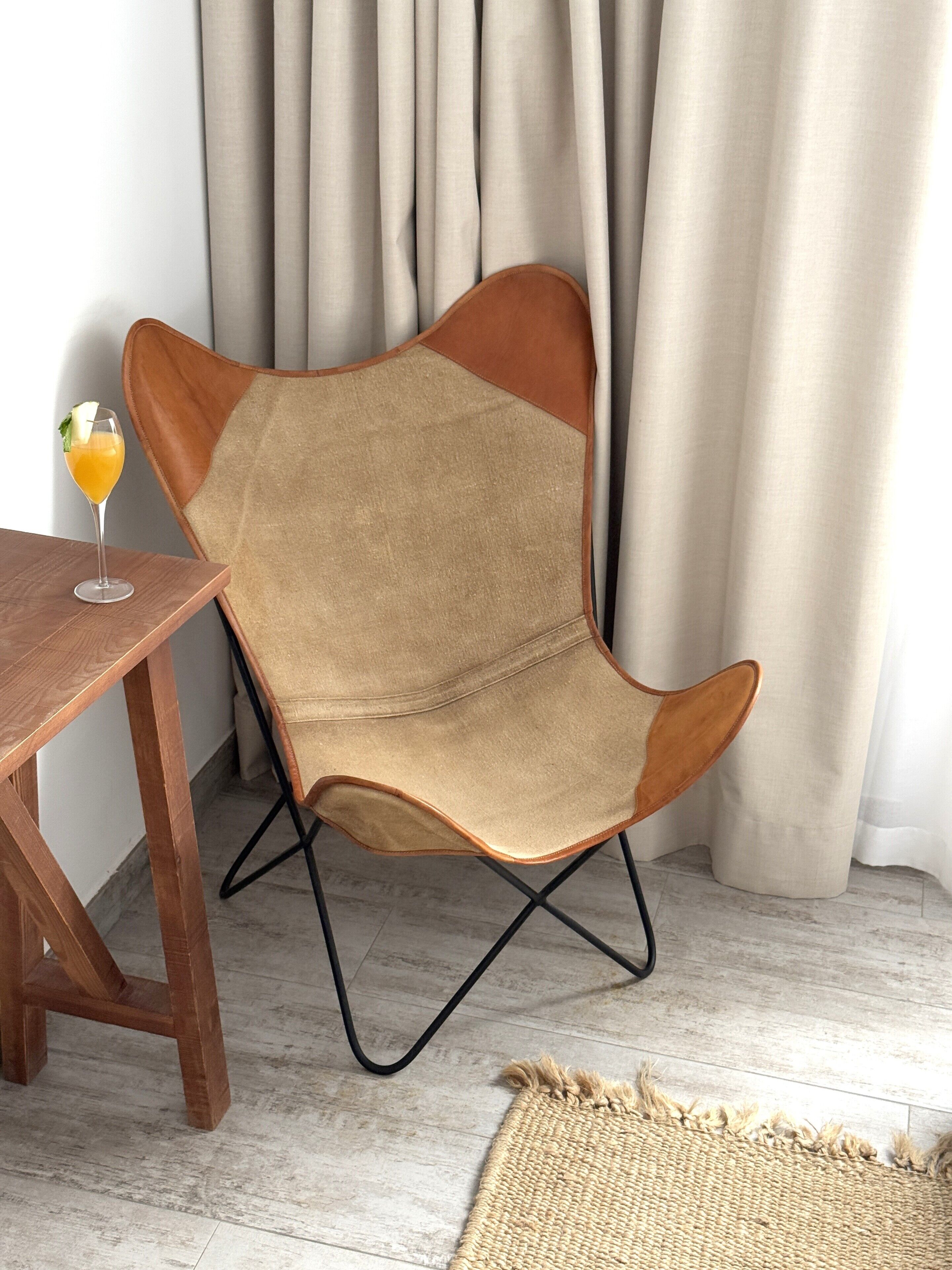 A chair with a unique design, a wooden table, and a glass of orange juice.