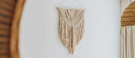 Una habitación con un sofá de cuero marrón, una mesa de centro redonda de madera y un tapiz de macramé en la pared.