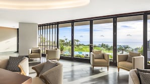 Amplia sala de estar con grandes ventanales que dan a una piscina y un campo de golf.