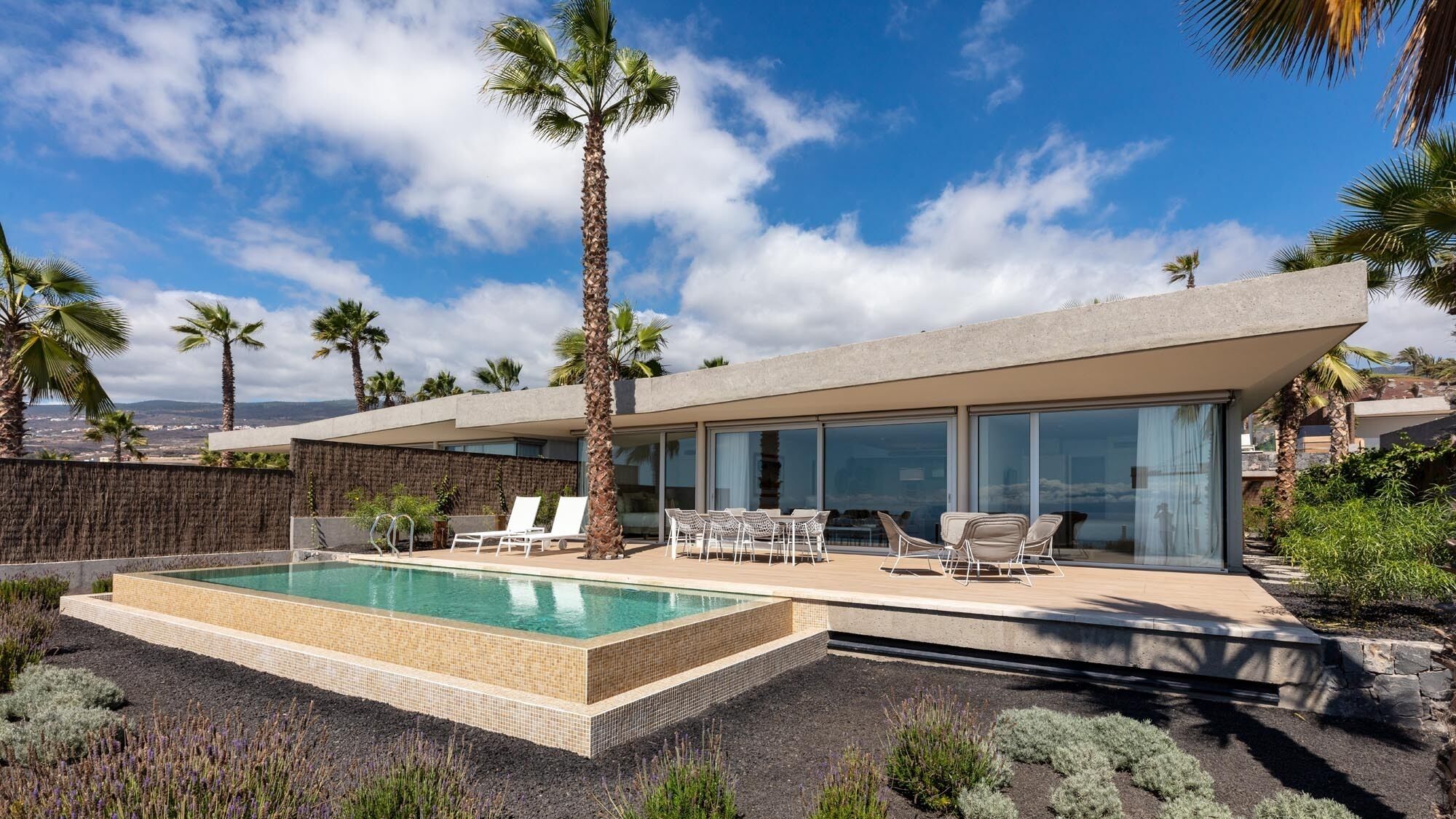 Et moderne hus med swimmingpool, udendørs siddepladser og udsigt over landskabet.