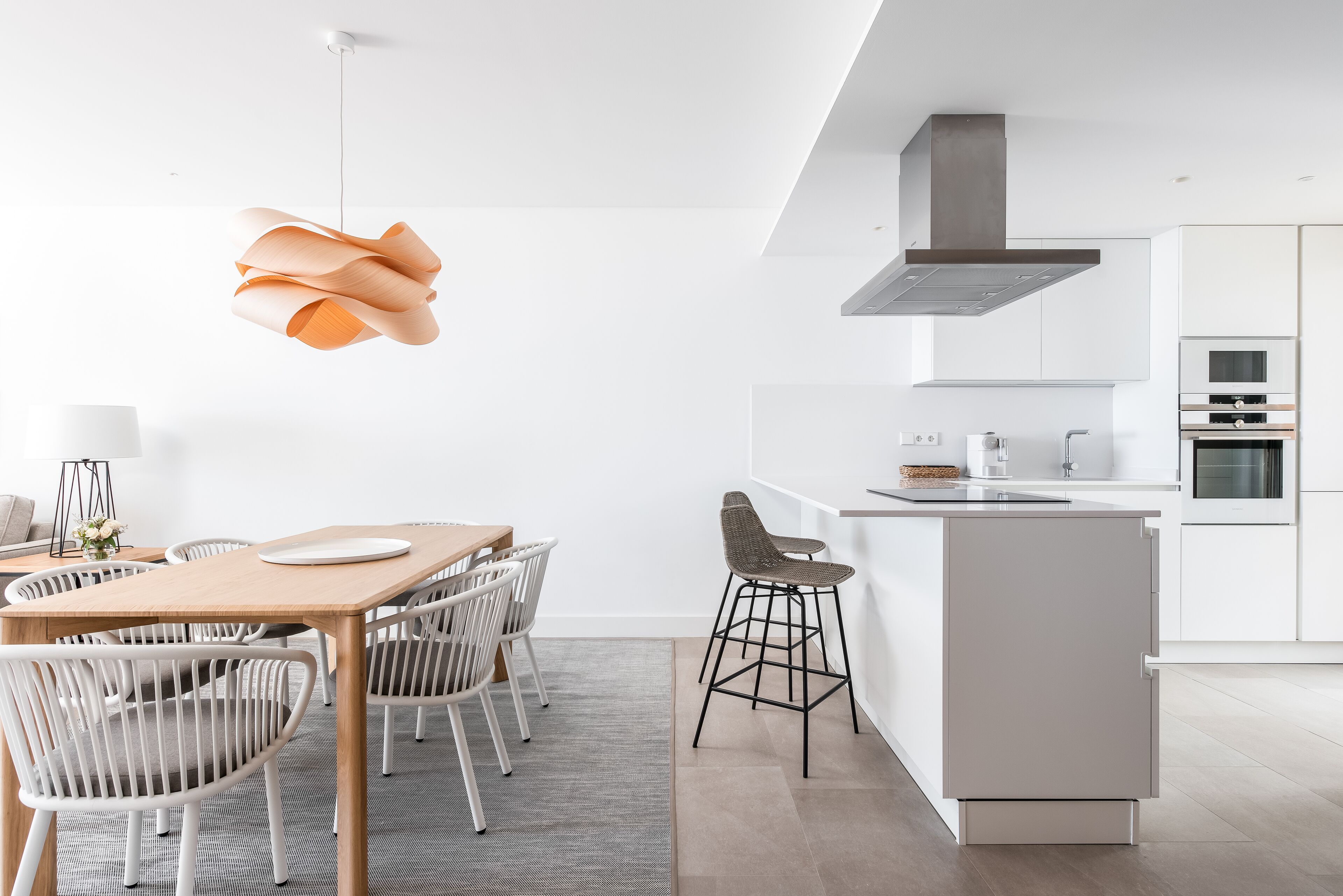 A modern kitchen with white cabinets, a central island, and a hanging light fixture.