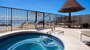 A pool area with a tiled edge, a wooden deck, and a wooden fence. - Amazing Bay View, Boat docks, and easy walk to the beach (South Padre Island)