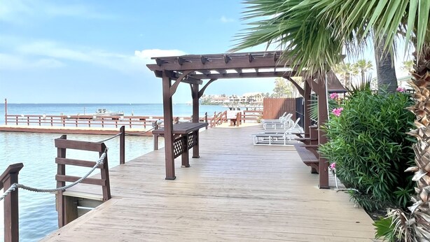 A wooden pier leading to a beach with a wooden pergola and benches. - Amazing Bay View, Boat docks, and easy walk to the beach (South Padre Island)