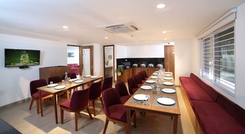 A dining area with a long table set for a meal, surrounded by chairs.