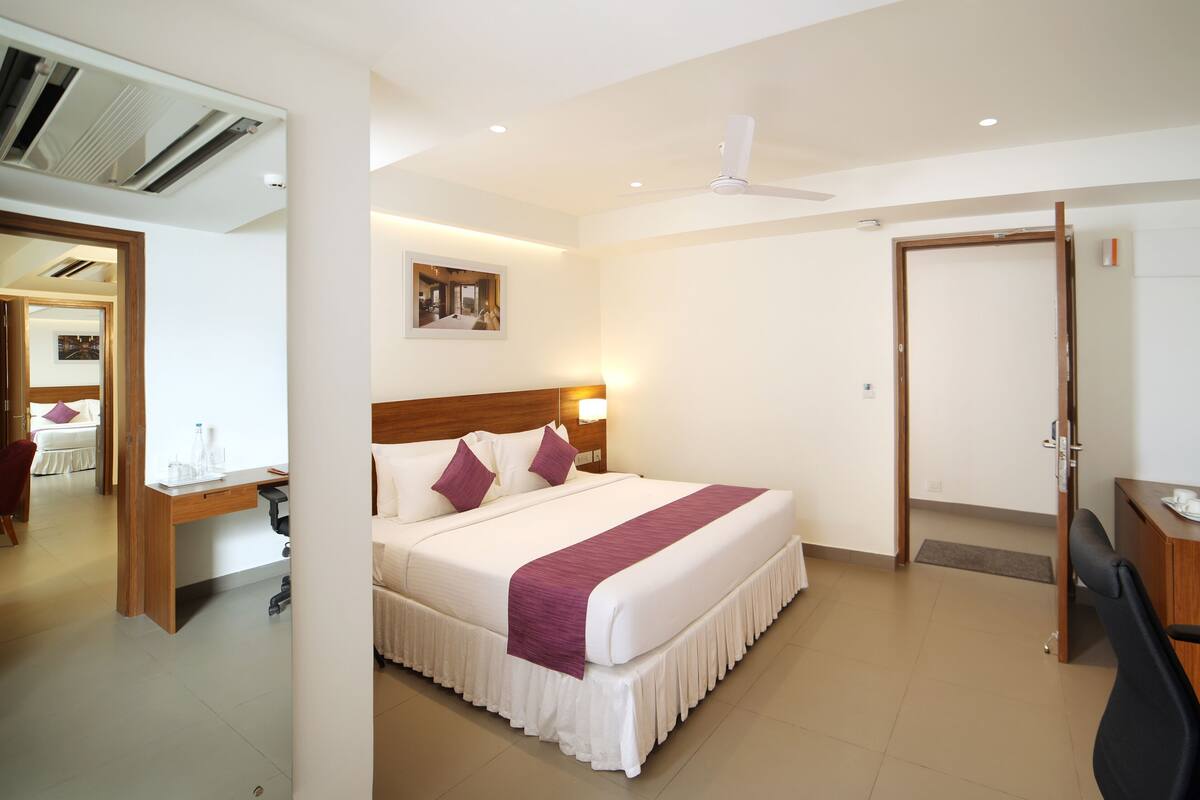 Habitación de hotel con cama, escritorio, silla y ventilador de techo.