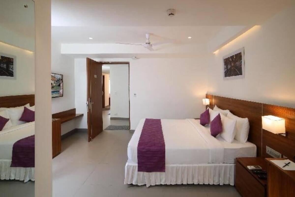 Una habitación de hotel con una cama grande, mesitas de noche, un escritorio y un ventilador de techo.