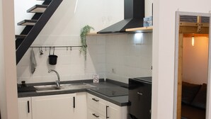 A compact kitchen with white cabinets, a black countertop, a built-in stove, and a black staircase leading to another level. - The Pearl of Neptune Tourist rental 600mt from the sea (Nettuno)