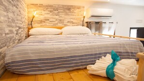 A hotel room with a wooden floor, a bed with striped bedding, a brick wall, and an air conditioning unit. - The Pearl of Neptune Tourist rental 600mt from the sea (Nettuno)