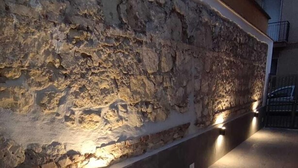 A stone wall with embedded lighting, a tiled floor, and a building in the background. - The Pearl of Neptune Tourist rental 600mt from the sea (Nettuno)