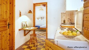 A compact kitchen with a stove, sink, and a small dining area with a table and stools.