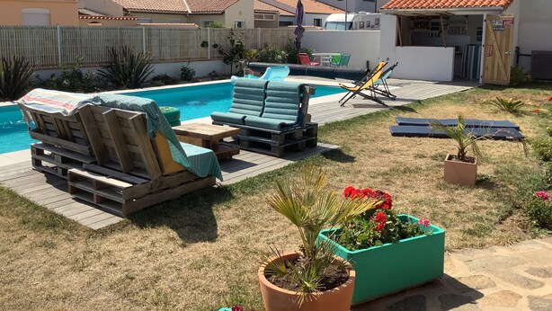 A backyard with a swimming pool, lounge chairs, and a small garden area.