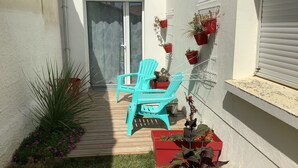 A small patio with a turquoise chair, potted plants, and a sliding glass door.