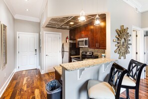 A kitchen with wooden cabinets, a granite countertop, and a stainless steel microwave.