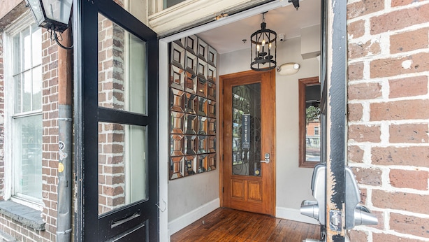 A wooden door with a glass panel, a brick wall, and a wooden floor. - Charming Downtown Studio One Block From The River by Lucky Savannah (Savannah)