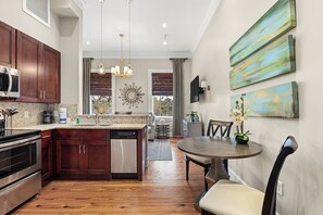 A modern kitchen with wooden cabinets, stainless steel appliances, and a dining area with a round table and chairs.