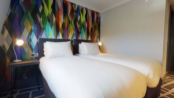 Ein Hotelzimmer mit einem Bett, zwei Nachttischen und einer Wand mit farbigem geometrischem Muster.