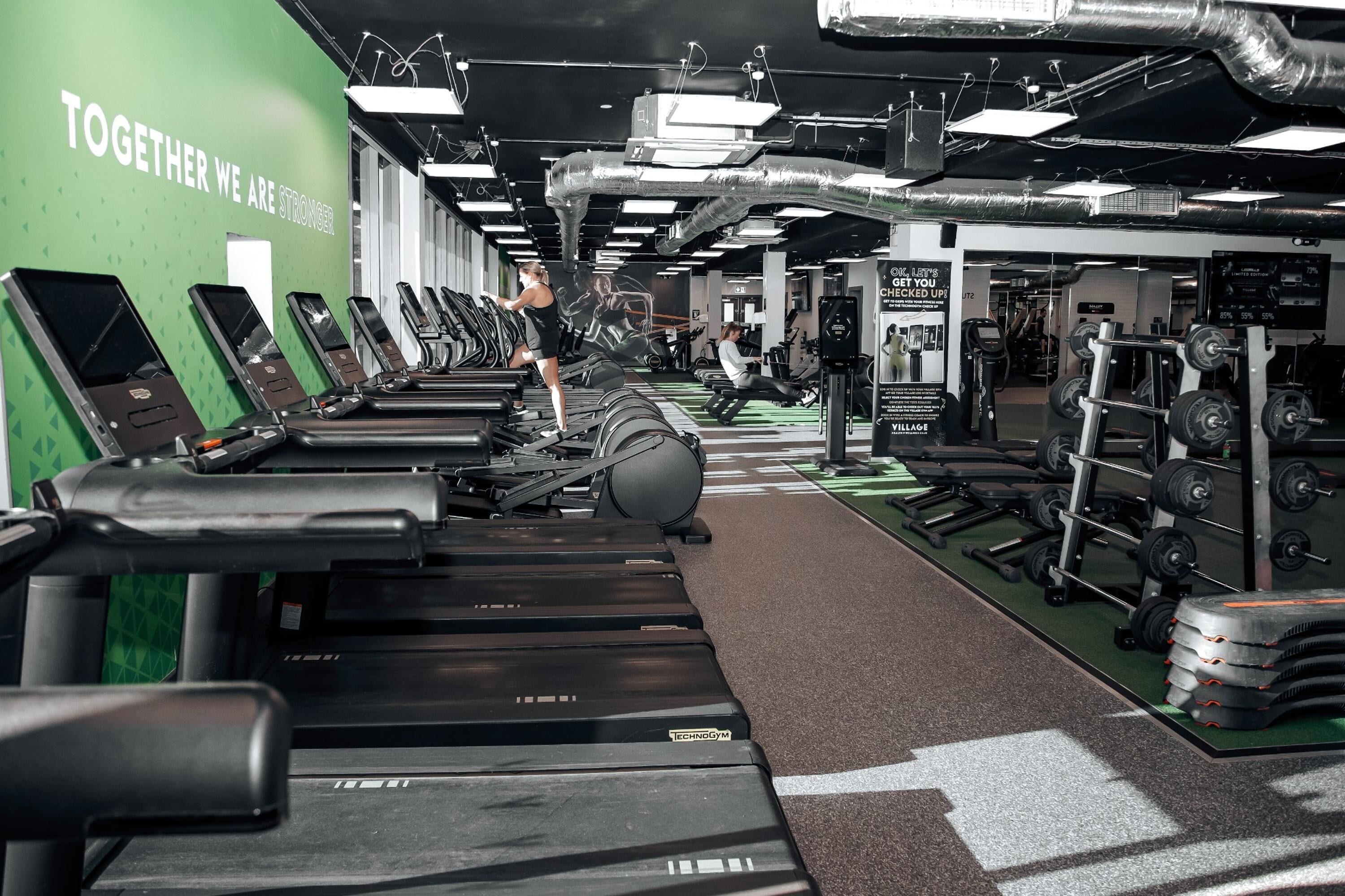 A gym with treadmills, weight machines, and a motivational wall.