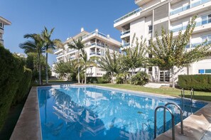 A swimming pool surrounded by greenery and modern apartment buildings.