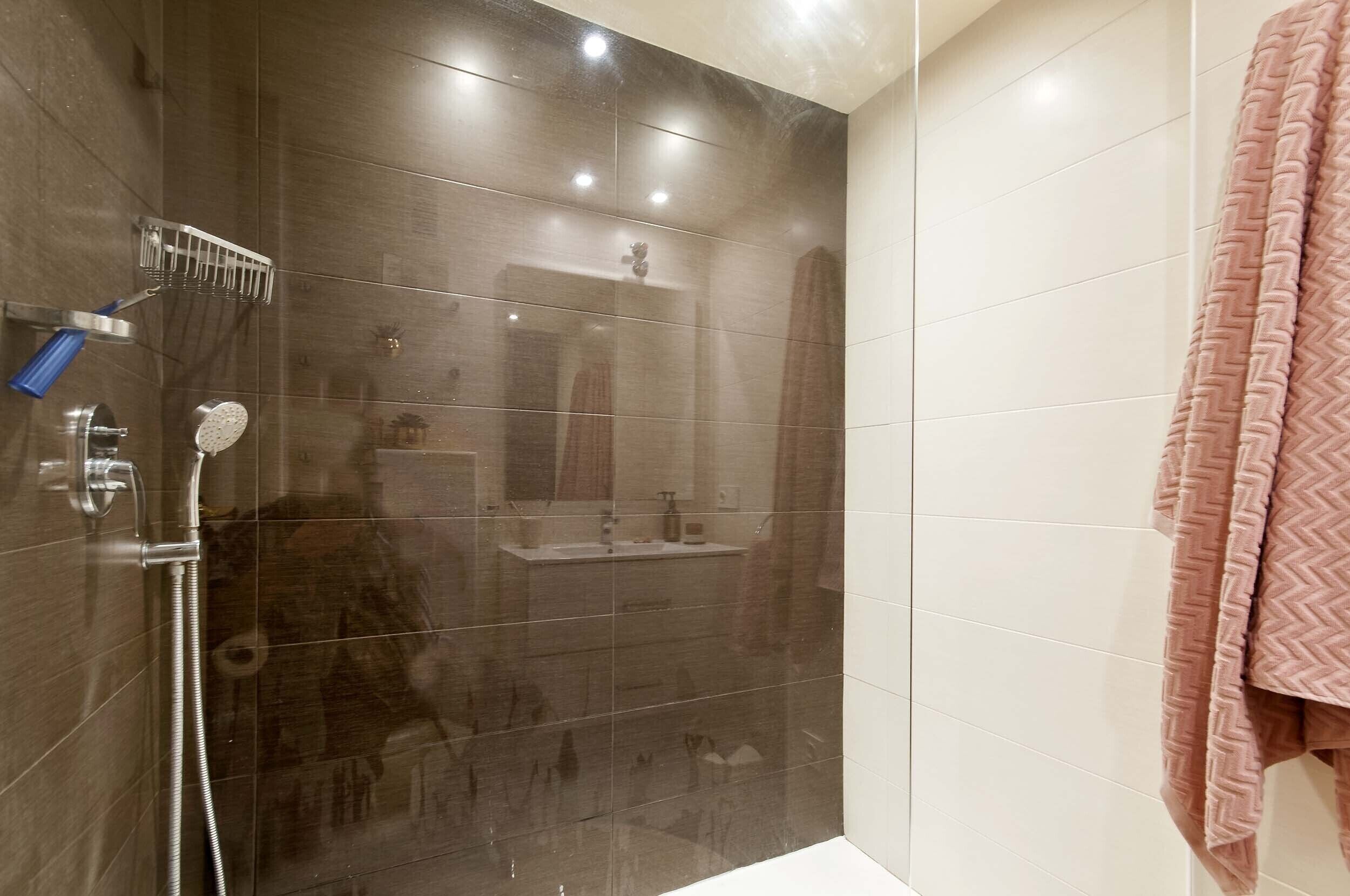 A modern bathroom with a glass shower enclosure, a sink, and a mirror.