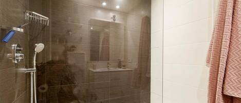 A modern bathroom with a glass shower enclosure, a sink, and a mirror.
