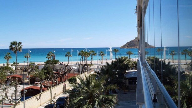 Blick auf die Küste mit Strand, Palmen und blauem Himmel.
