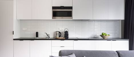 Una cocina moderna con armarios blancos, horno integrado y encimera negra.