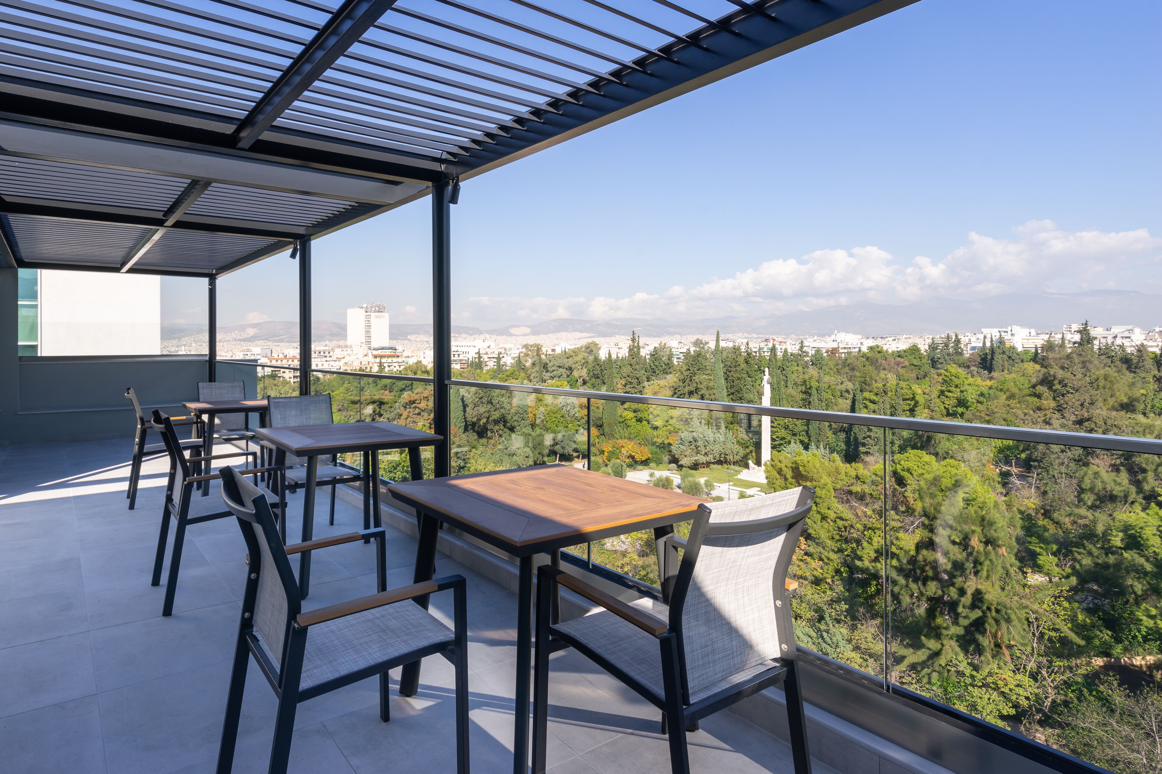 A balcony with a view of a cityscape and greenery.