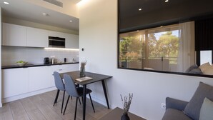 Una cocina moderna con armarios blancos, encimera negra y un comedor con mesa y sillas.